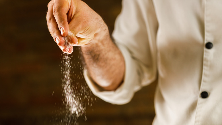 Chef adding salt by hand