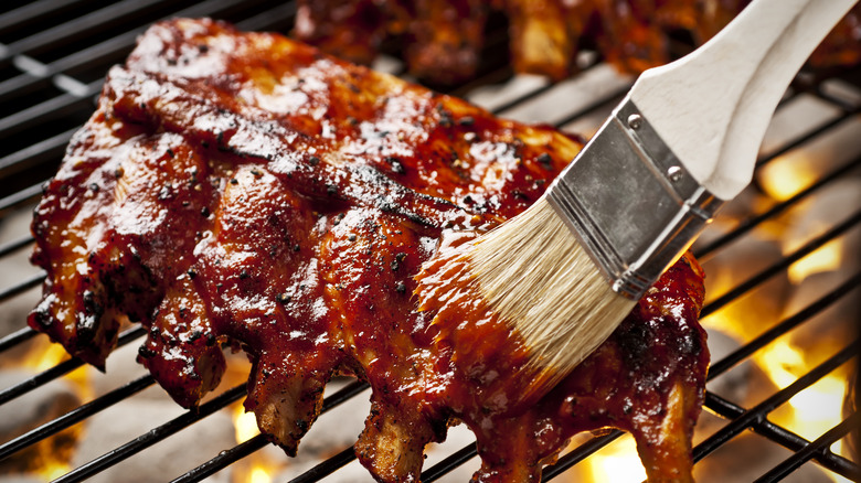 Brushing barbecue sauce while barbecuing ribs