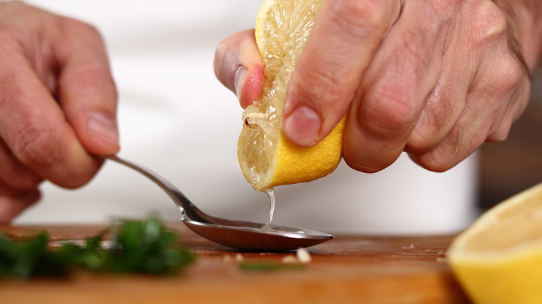 Chef squeezing lemon juice into spoon