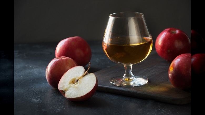 glass surrounded by apples