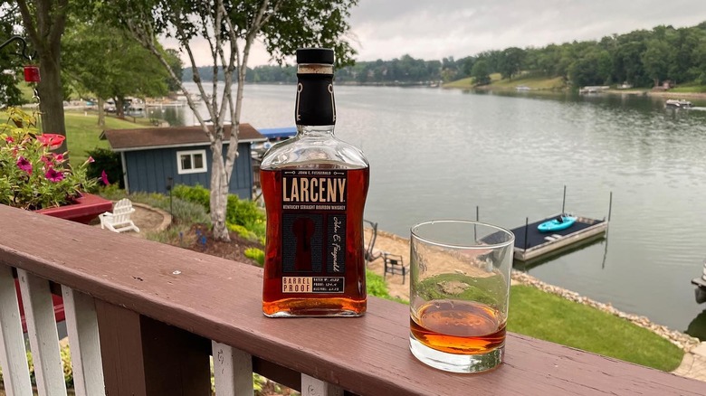 Bottle of Larceny bourbon with glass on waterfront