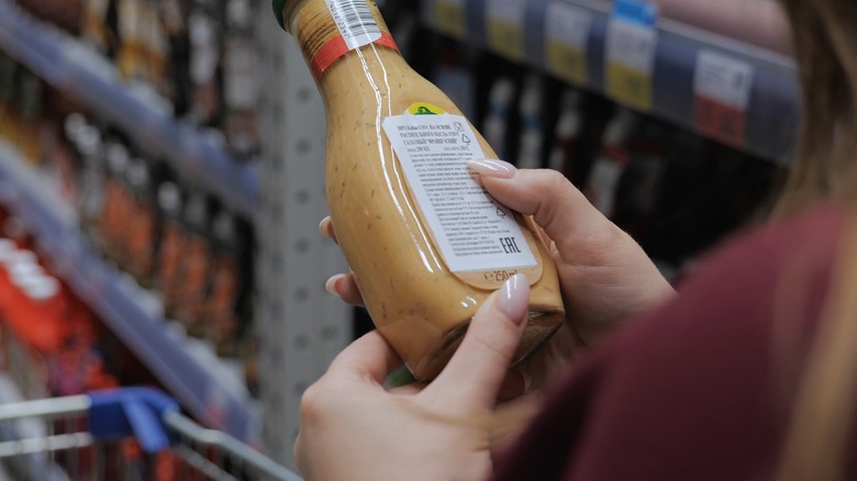 person reading salad dressing bottle