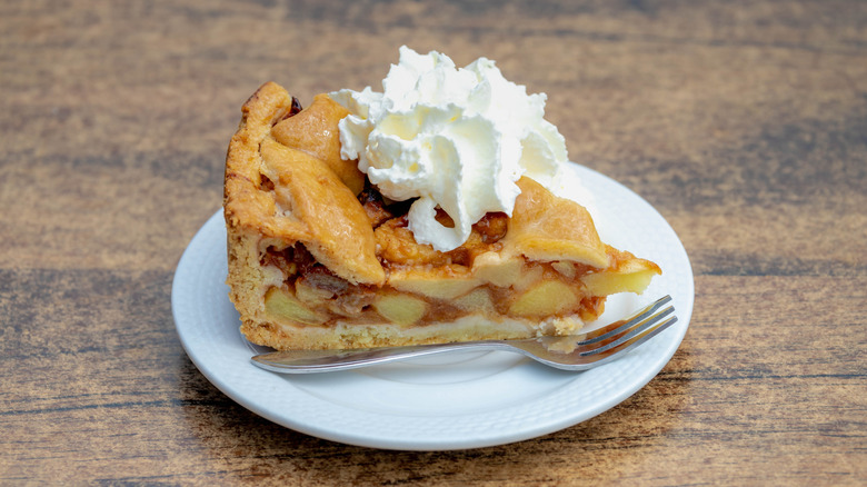 Whipped cream on slice of apple pie