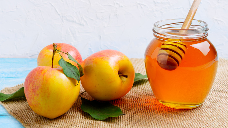 apples and jar of honey with dipper