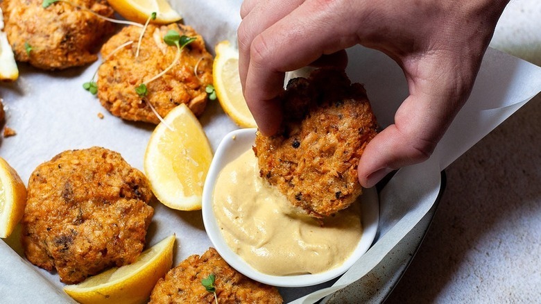 dipping salmon patty in creamy sauce