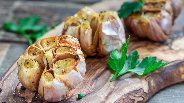 bulbs of roasted garlic on rustic wooden board