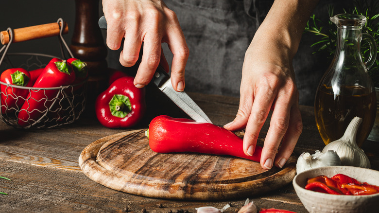 hands chopping chilis on cutting board