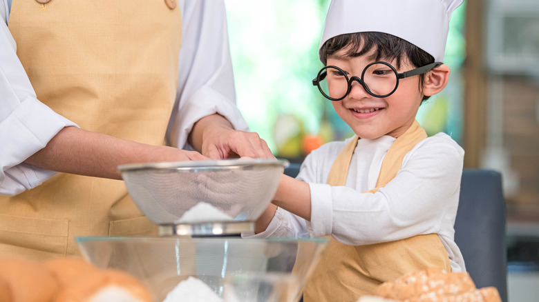 child baking with colander