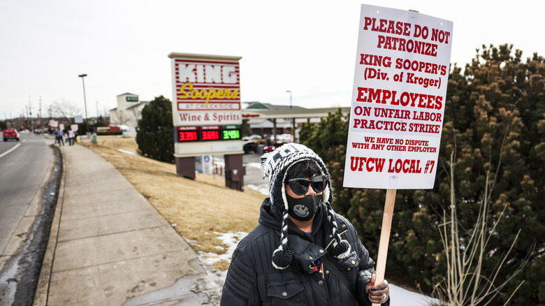 King Soopers employee picketing with red and white sign