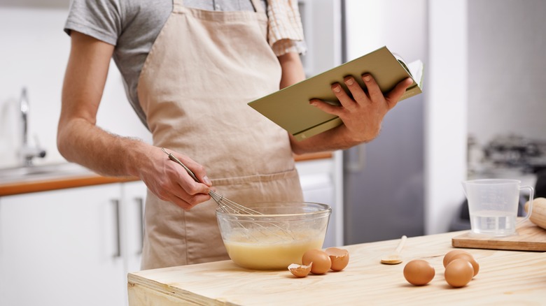 Person holding cookbook and whisking