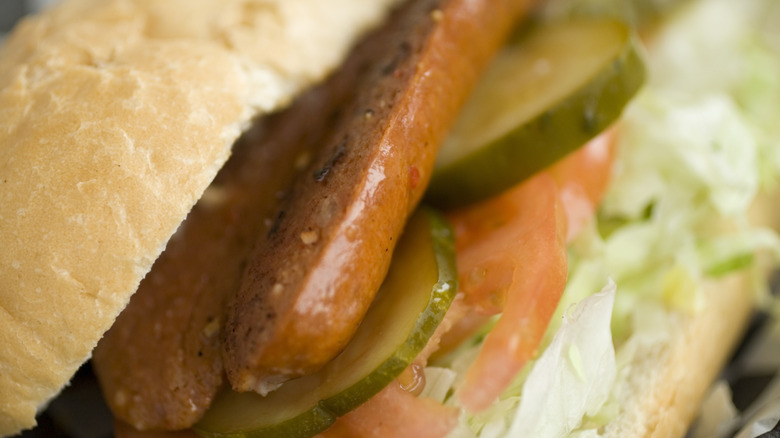 Spicy sausage po'boy sandwich with cucumber, tomato, and lettuce