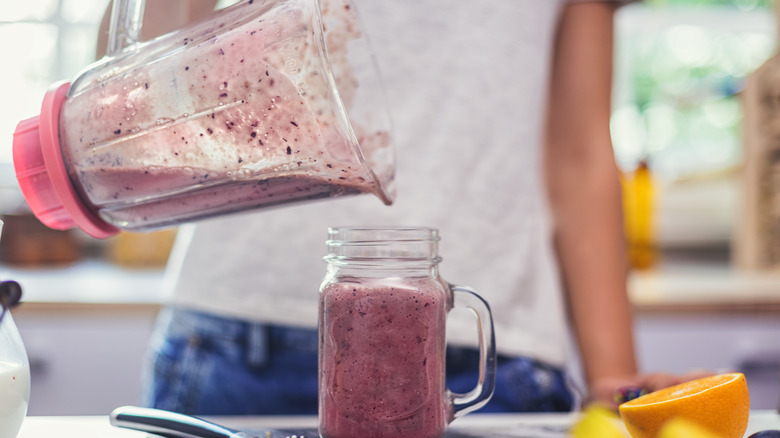 pouring cranberry smoothie from blender