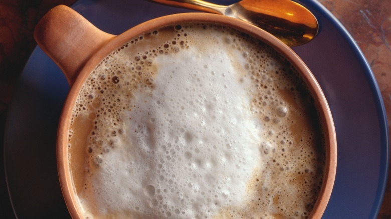 A foamy cappuccino on a blue plate