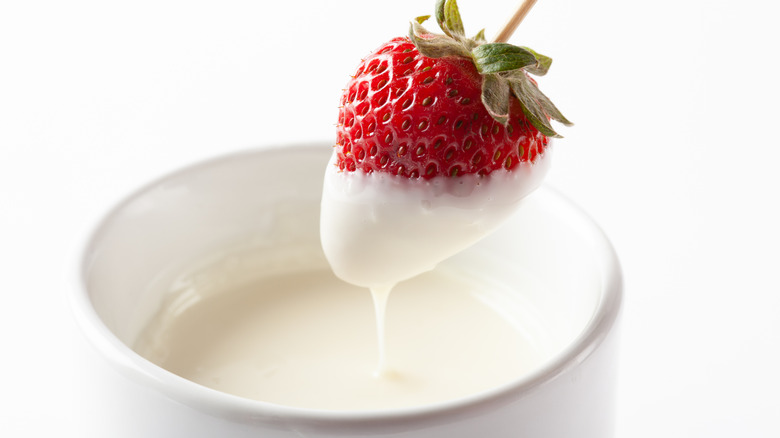 Strawberry being dipped in yogurt