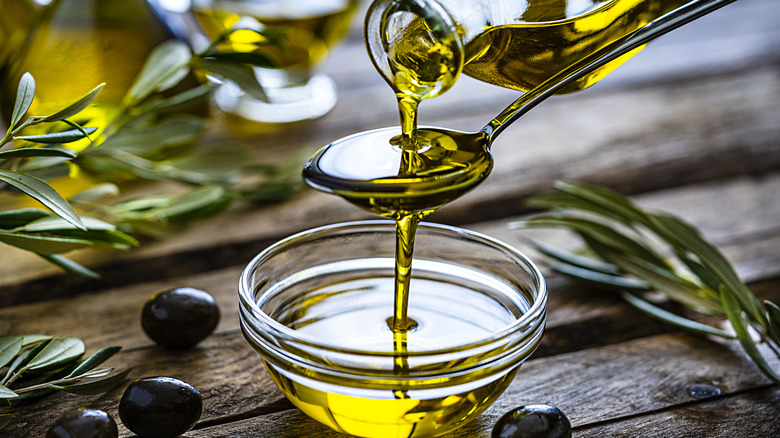 Olive oil being poured over a spoon and into a tiny serving bowl.