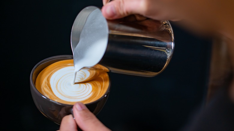 Hot milk being poured onto coffee