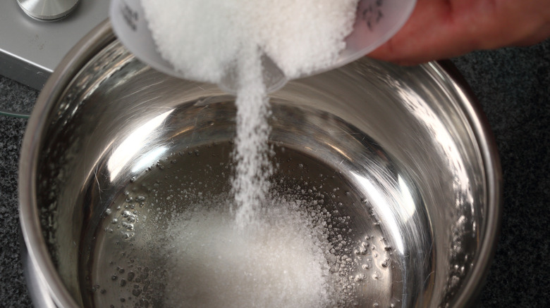 Sugar being poured into saucepan