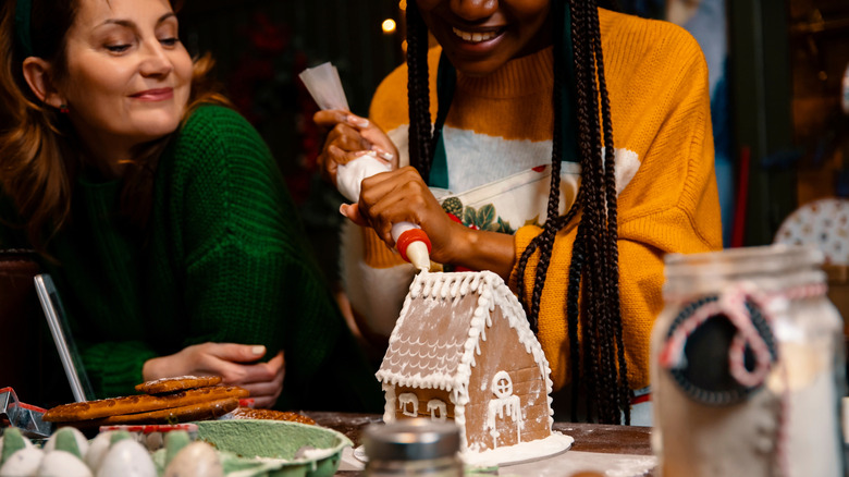 People constructing a gingerbread house