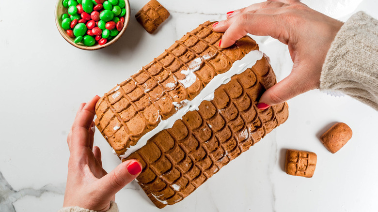 Hands assembling a gingerbread house