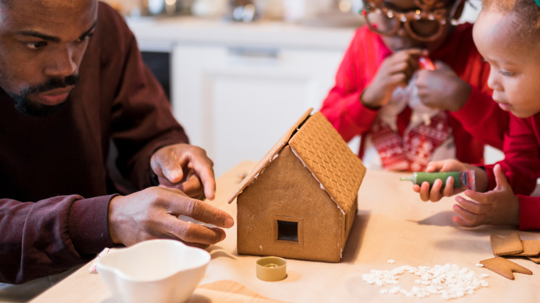 A family assembling a gingerbread house