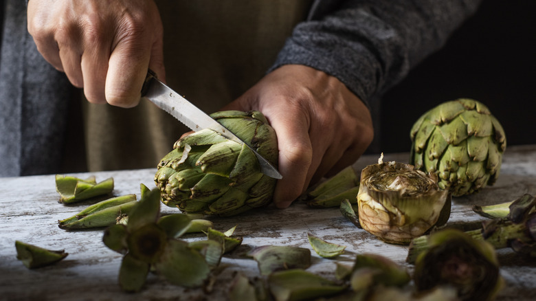 man cutting fresh artichoke