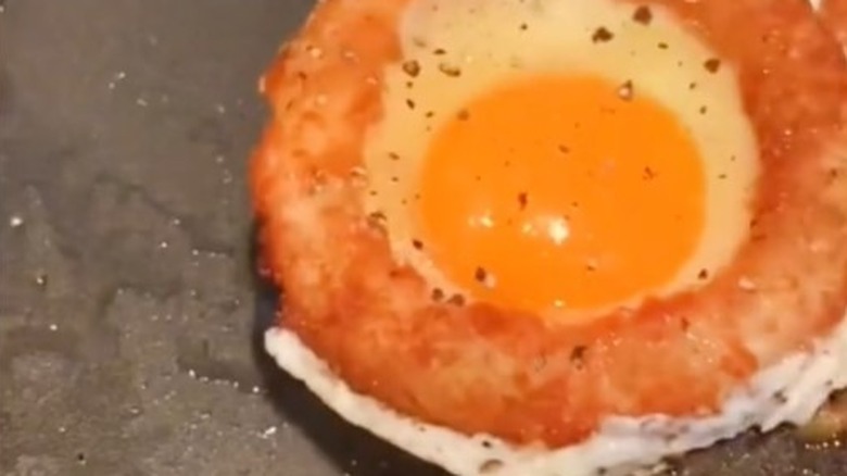 fried egg in a breaded onion ring in frying pan