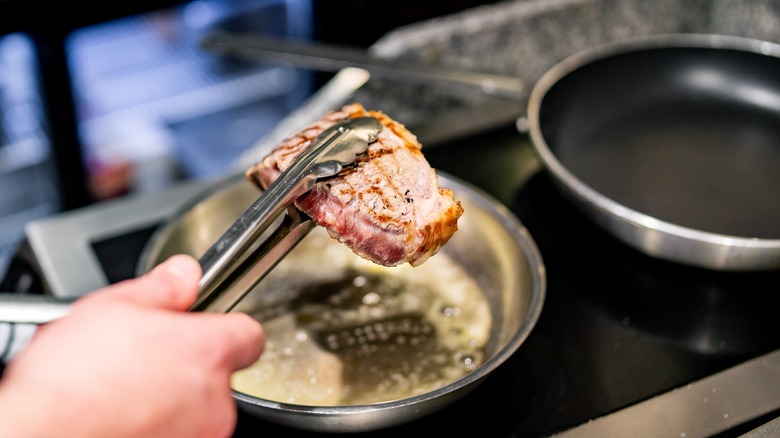 holding seared steak in tongs