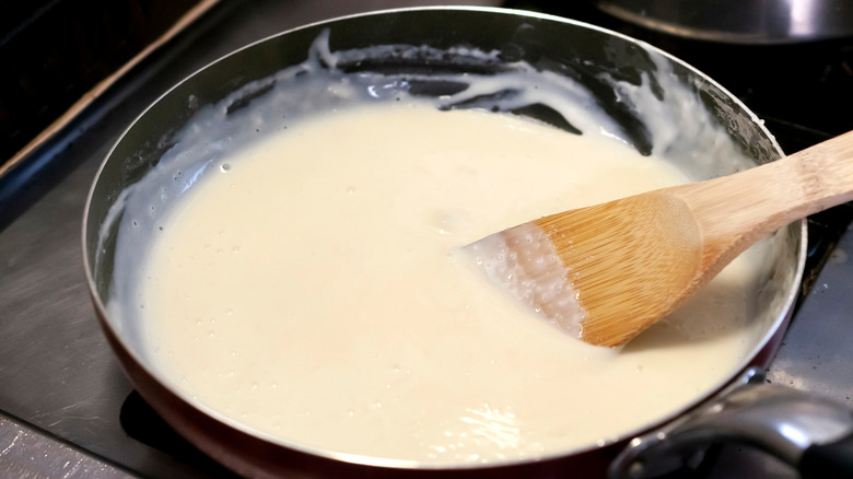 Béchamel sauce in a pan with a wooden spoon