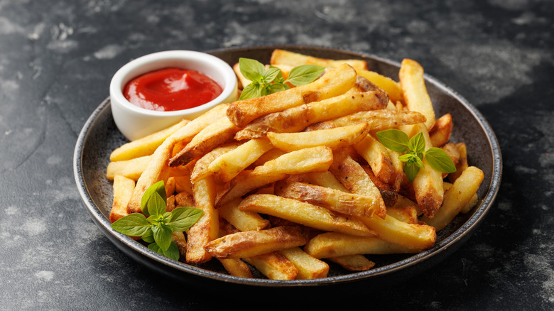 A plate of french fries with ketchup on the side