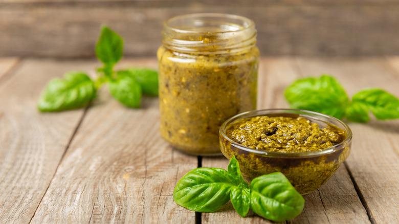 A jar of pesto with a glass bowl on the side