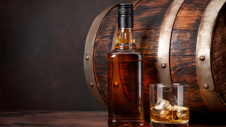 Bottle and glass of bourbon with barrel