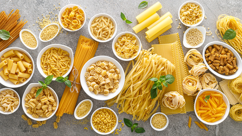 Many types of uncooked pasta in bowls and on counter