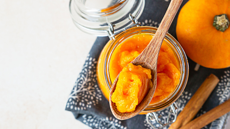 Pumpkin puree in a jar with a spoon and spices on the side