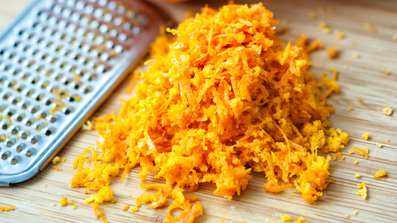 A pile of orange zest beside a grater