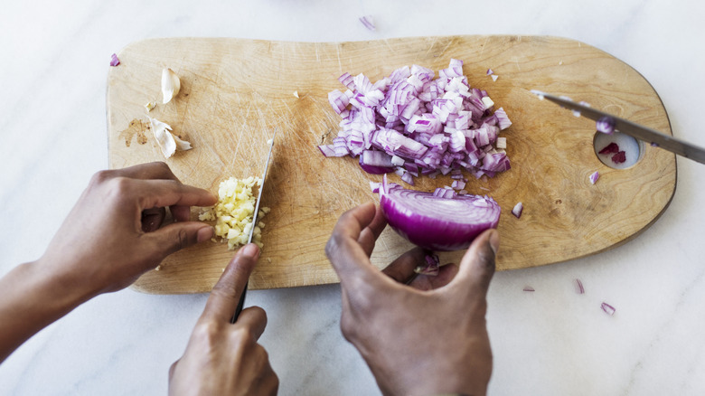 hands chopping onion and garlic