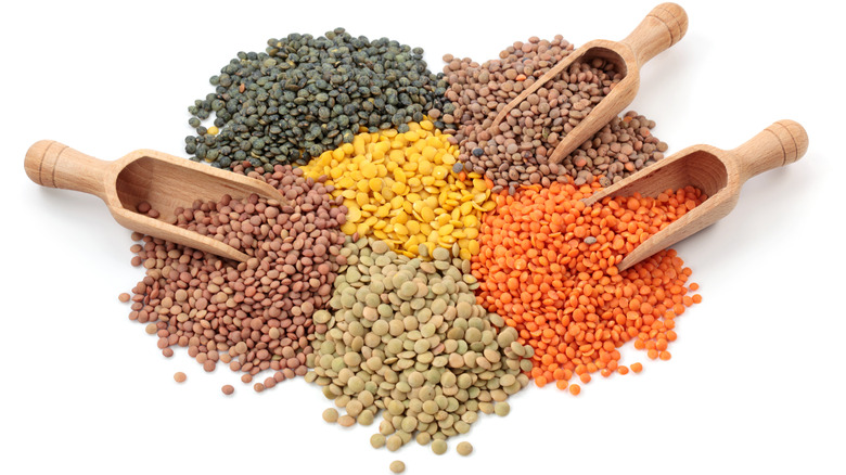 piles of different color lentils and wooden scoops