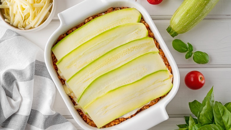 zucchini lasagna in casserole dish surrounded by vegetables