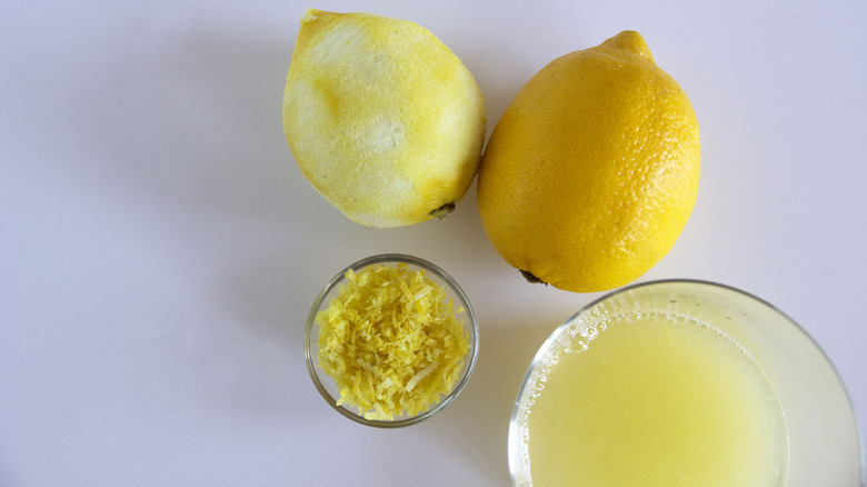 Lemons with glass bowl of lemon juice and zest