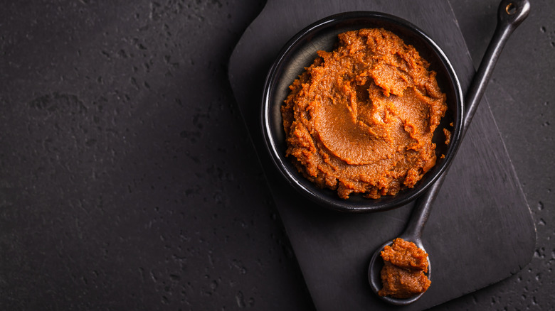 A black bowl of miso paste with a spoonful