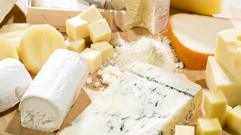 A selection of cheeses on a wooden cheese board