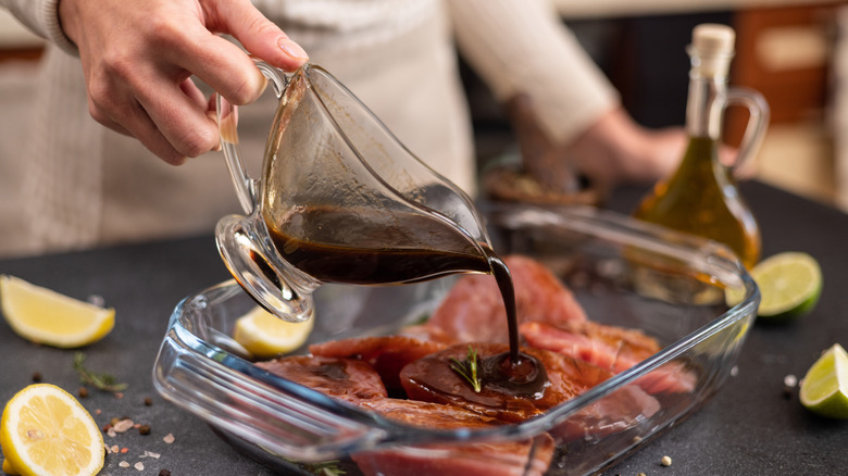 person pouring marinade over meat