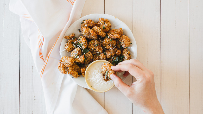 hand dipping shrimp into dipping sauce