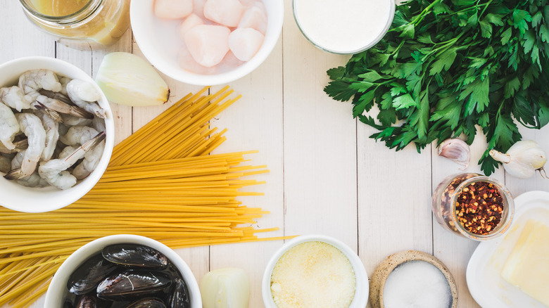 ingredients, dry linguine noodles, scallops in bowl, shrirmp in bowl, freshly parsley