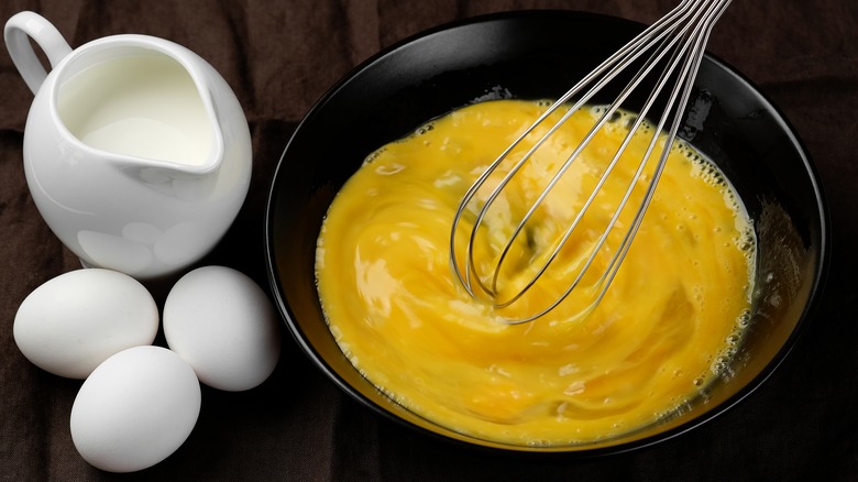 Eggs being whisked with balloon whisk with milk