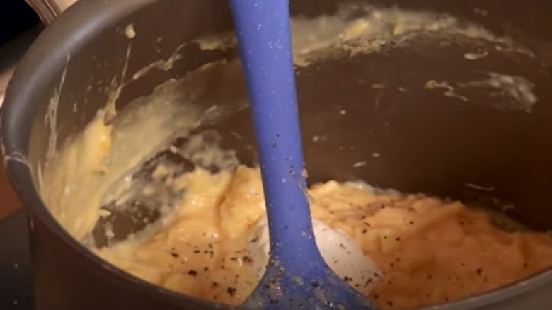 Scrambled eggs in saucepan with spatula