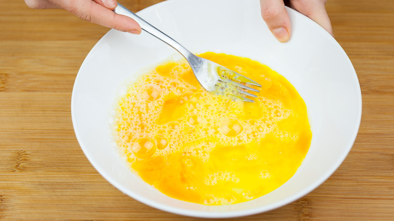 Eggs being whisked in a bowl with a fork