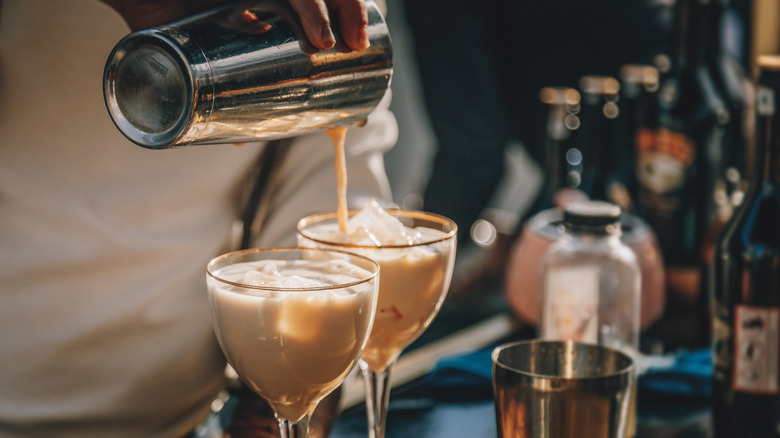 Bartender pouring milky cocktails from a shaker