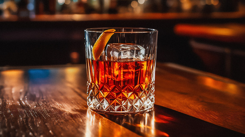 Old Fashioned cocktail sitting on a wooden table in a bar