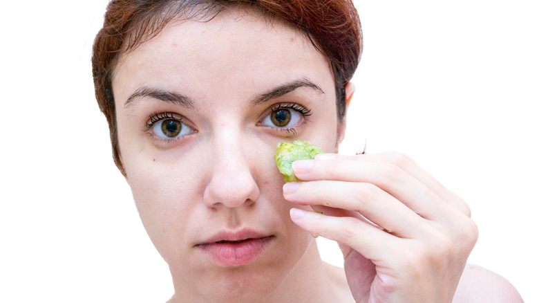 Person holding cucumber to face