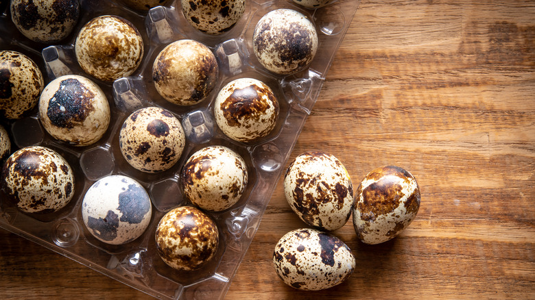 open carton of quail eggs on a wooden background